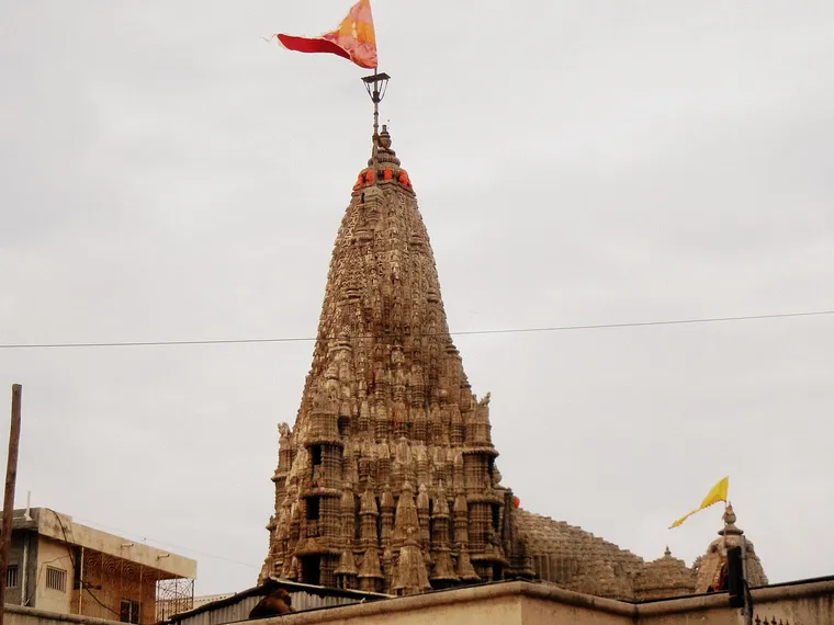 The carved sandstone spire of the Dwarkadhish Temple in Dwarka rising above the rooftops, with its flag flying from the top