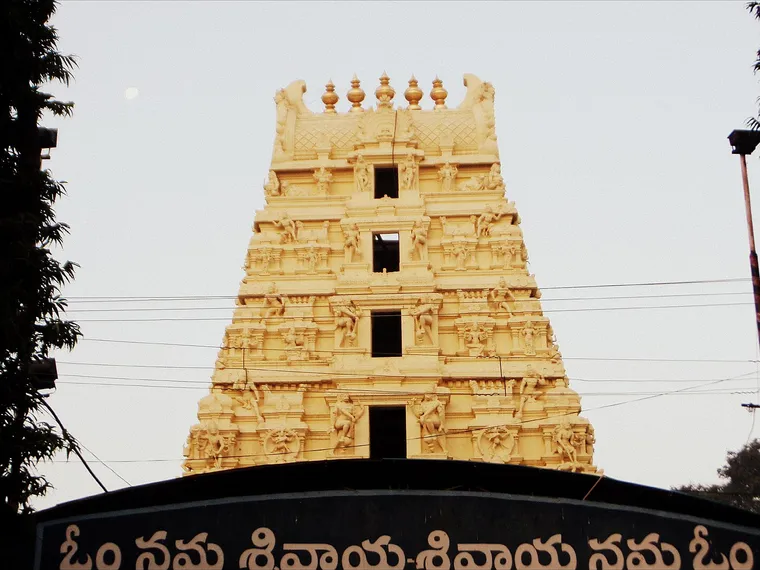 The gilded, carved gopuram of the Mallikarjuna Temple at Srisailam above an arch lettered Om Namah Shivaya in Telugu