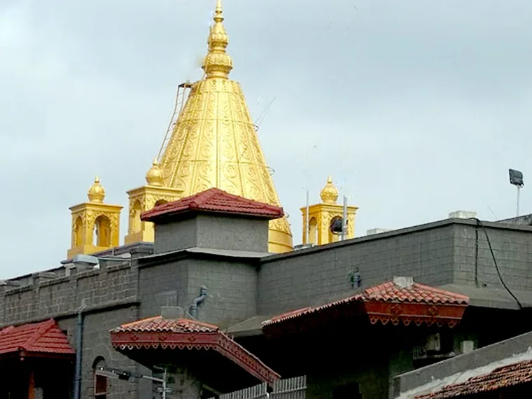 The gold-plated shikhara of the Sai Baba Samadhi Mandir at Shirdi rising above the grey stone walls and tiled roofs of the temple complex
